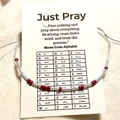 a bracelet with red beads on it sitting on top of a piece of paper that says just pray