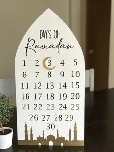 a wooden calendar sitting on top of a table next to a small potted plant