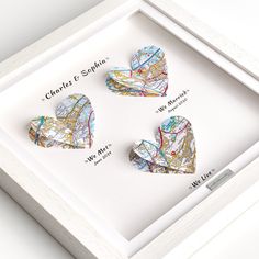 three maps shaped like hearts in a white shadow box with the names of each location