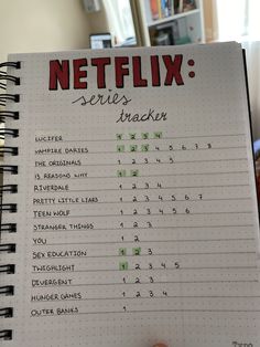 a hand holding a notebook with the words netflix series tracker written on it