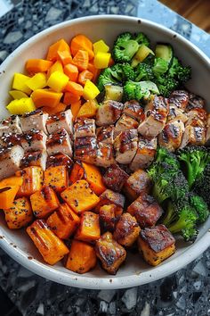 a white bowl filled with meat and veggies on top of a marble counter