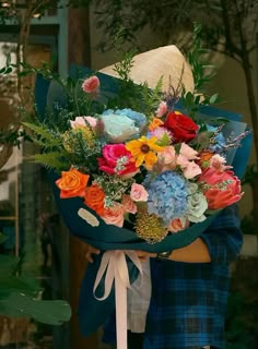 a woman holding a bouquet of flowers in her arms and wearing a hat on top of her head