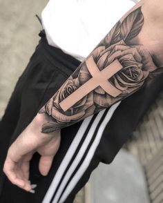 a man with a cross and roses tattoo on his arm