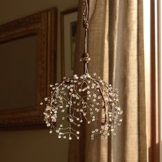 a chandelier with white flowers hanging from it's sides in front of a window