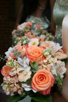 two bridesmaids holding bouquets of peach and white flowers in front of each other