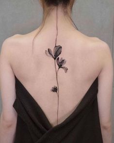 the back of a woman's neck with a flower tattoo on her left side