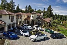 several cars are parked in front of a large house with driveway and trees on the other side