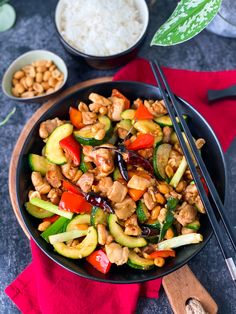 a bowl filled with stir fry vegetables and chopsticks on top of a table