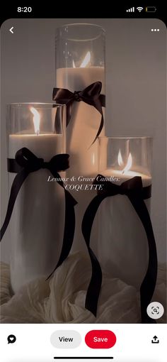 three candles are sitting in front of each other on a bed with white sheets and black ribbon