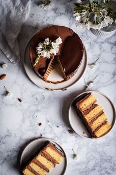 three plates with slices of cake on them and flowers in the middle one plate has a slice missing from it