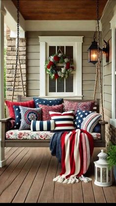 a porch swing with pillows and blankets on the front porch, decorated for memorial day