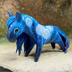 a blue toy horse is standing on the ground