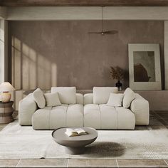 a large white couch sitting in a living room next to a table and lamp on top of a rug