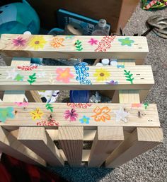 three wooden pallets with flowers painted on them sitting on the floor next to toys