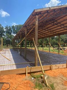 a wooden structure under construction in the middle of a field with dirt on the ground