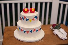 a three tiered cake with two candles on top and bunting flags around it