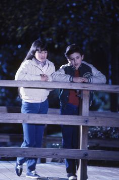 two young people standing on a wooden bridge