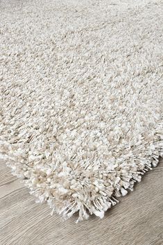 a large white rug on top of a wooden floor