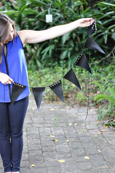 a woman in blue shirt holding black paper pennants