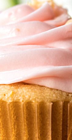 a pink frosted cupcake sitting on top of a white plate