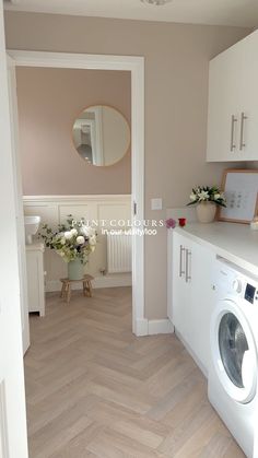 a washer and dryer are in the corner of this laundry room with wood flooring