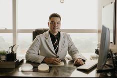 a man in a suit sitting at a desk with a computer and mouse on it