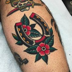 an old school style tattoo on the leg of a man with flowers and a skull