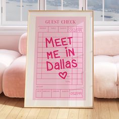 a pink poster with the words meet me in dallas on it next to a couch