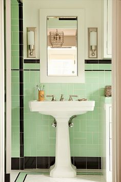 a white pedestal sink sitting under a mirror next to a green tiled bathroom counter top