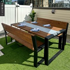 a wooden bench sitting on top of a grass covered field next to a table and benches