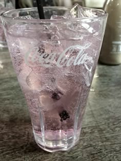 a glass filled with ice and water on top of a table