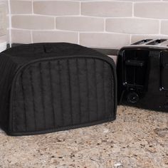 two black toasters sitting next to each other on a counter