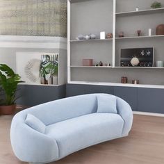 a blue couch sitting in the middle of a living room next to a book shelf