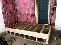 an unfinished bed frame in the middle of a room with pink insulation on the walls