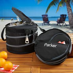 two cooler bags sitting on top of a wooden table next to oranges and an umbrella