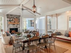 a dining room and living room with white walls, wood flooring and large windows