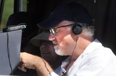 a man with headphones on sitting next to another man in a truck looking at something