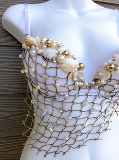 a white mannequin with gold and pearls on it