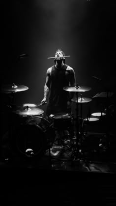 a man standing on top of a drum set in front of microphones and drumsticks