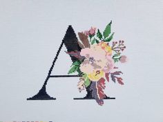 a cross stitched letter with flowers on it