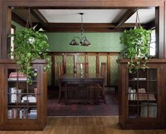 the dining room is decorated in green and wood with potted plants hanging from the ceiling