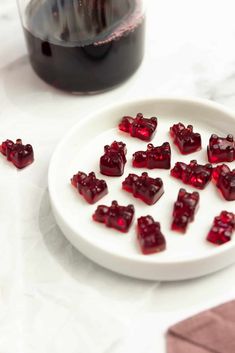 small pieces of red jelly on a plate next to a glass of wine