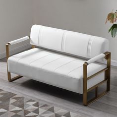 a white leather couch sitting on top of a hard wood floor next to a potted plant