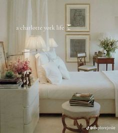 a bedroom with white bedding and pictures on the wall