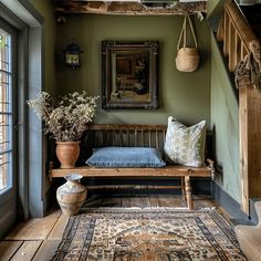 a wooden bench sitting in the middle of a room next to a rug and potted plants