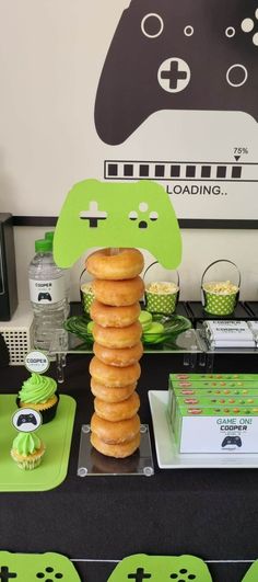 a table topped with donuts and cupcakes next to a video game controller