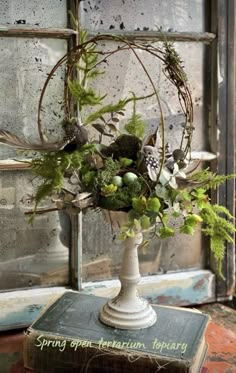 a vase filled with lots of green flowers and greenery on top of a table