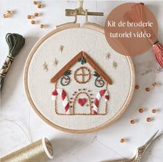 a cross stitch house with candy canes on the table next to scissors and thread