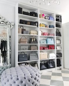 a room filled with lots of purses and handbags on shelves next to a mirror