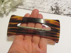 "An extra huge vintage 1980's French hair barrette with a gorgeous brown tortoiseshell striped pattern. The hair clip measures 5\" long and made of semi-transparent plastic with pretty varying shades of brown colors. The closure is silver tone metal bar that is held by tension in a c-clasp style closure. Quintessential 80's when big hair was popular. Super fun! -Age: 1980's -Material(s): Plastic -Size: 5\" long by 2\" wide -Brand / Hallmarks: Unsigned French Condition: New old stock (NOS), vintage store stock that was never worn. Very minimal signs of age or wear. More Vintage Hair Accessories: http://etsy.me/2dn7BHB" Striped Hair, 1980s Hair, Vintage Hair Accessories, French Hair, French Barrette, Metal Bar, Semi Transparent, Barrette Clip, Vintage Store